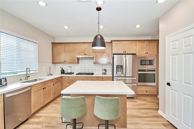 3430 E Foxglove Way, Ontario, CA 91761 - kitchen with stainless steel appliances, a sink, under cabinet range hood, backsplash, and light wood-style flooring