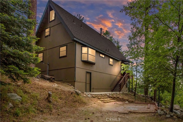 6429 Cedar Ave, Angelus Oaks, CA 92305 - property exterior at dusk featuring stairs and a shingled roof