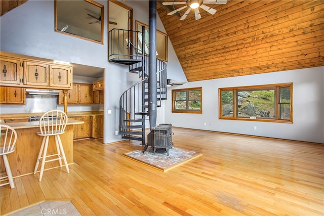 6429 Cedar Ave, Angelus Oaks, CA 92305 - living room featuring a wood stove, a ceiling fan, high vaulted ceiling, stairway, and light wood-style flooring