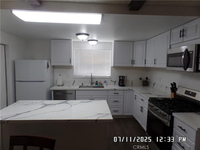 1676 Dumbarton Ave, San Bernardino, CA 92404 - kitchen with appliances with stainless steel finishes, dark wood-style floors, white cabinets, light stone counters, and a kitchen island