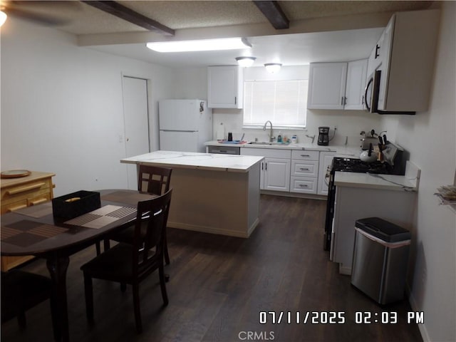 1676 Dumbarton Ave, San Bernardino, CA 92404 - kitchen featuring freestanding refrigerator, light countertops, dark wood-type flooring, a center island, and white cabinetry