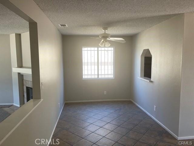 900 Raquel Ct, Hemet, CA 92545 - spare room featuring a ceiling fan, a textured ceiling, a tile fireplace, and baseboards