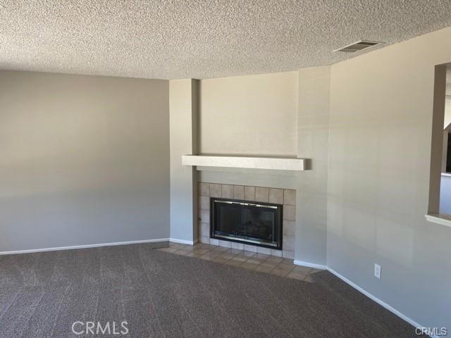 900 Raquel Ct, Hemet, CA 92545 - unfurnished living room with carpet flooring, a textured ceiling, a tile fireplace, and baseboards