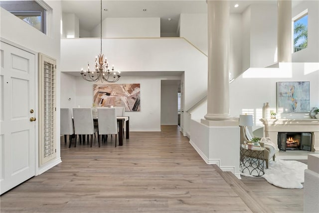 11 Porto Cervo Dr, Dana Point, CA 92629 - entrance foyer featuring a high ceiling, a chandelier, wood finished floors, a glass covered fireplace, and decorative columns