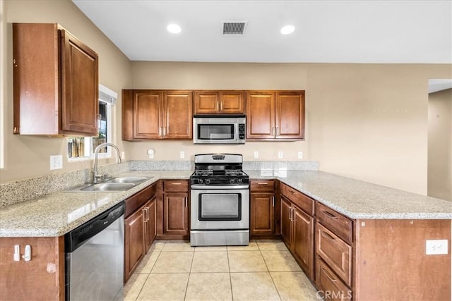 7415 Saladin Ave Unit 29, Palms, CA 92277 - kitchen with stainless steel appliances, a sink, a peninsula, brown cabinetry, and light tile patterned floors