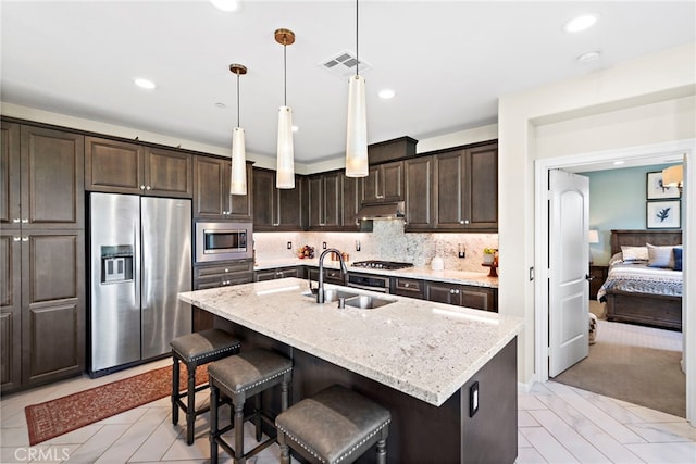 2 Jaripol Cir, Rancho Mission Viejo, CA 92694 - kitchen with stainless steel appliances, a sink, under cabinet range hood, dark brown cabinets, and light stone counters
