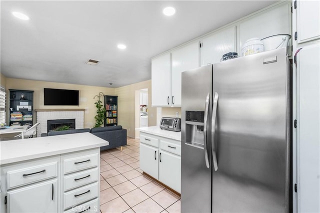 37398 Harrow Ct, Palmdale, CA 93550 - kitchen featuring stainless steel refrigerator with ice dispenser, light countertops, a brick fireplace, white cabinetry, and recessed lighting