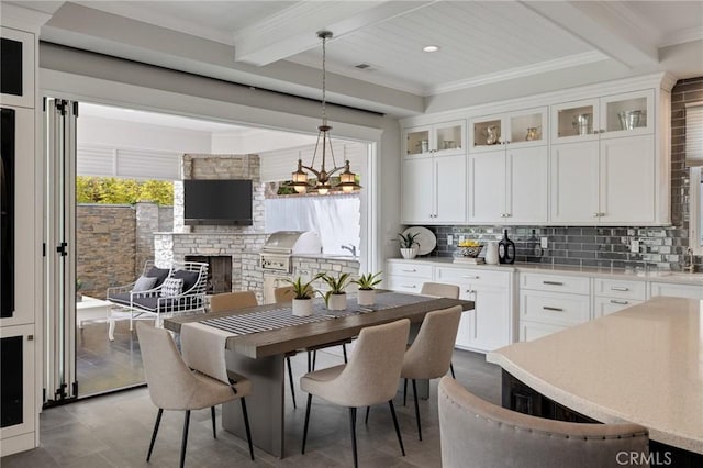 2711 Elm Ave, Manhattan Beach, CA 90266 - dining space with beam ceiling, plenty of natural light, a large fireplace, ornamental molding, and a chandelier