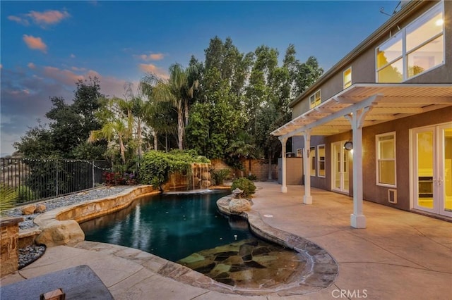 24274 Reyes Adobe Way, Valencia, CA 91354 - pool at dusk featuring a fenced backyard, a patio area, and french doors