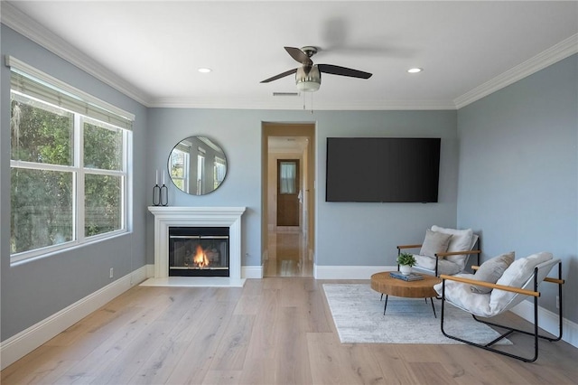 24274 Reyes Adobe Way, Valencia, CA 91354 - living area with a glass covered fireplace, light wood-style floors, a ceiling fan, baseboards, and crown molding