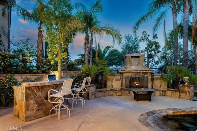 24274 Reyes Adobe Way, Valencia, CA 91354 - patio terrace at dusk featuring an outdoor stone fireplace and a patio area