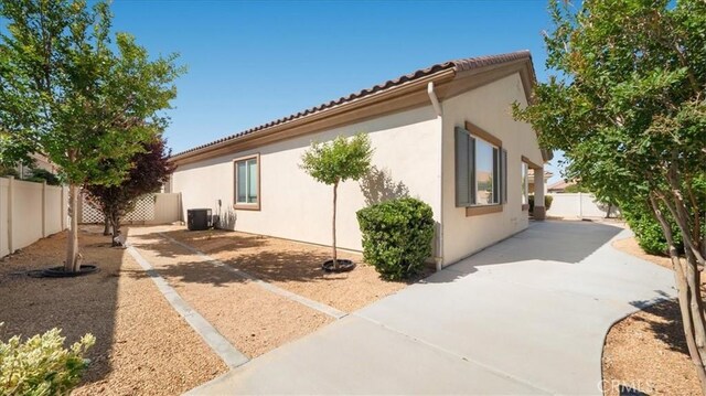19484 Vermillion Ln, Apple Valley, CA 92308 - view of side of property featuring cooling unit, a fenced backyard, a patio, and stucco siding