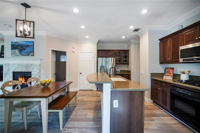 1 Evergreen Rd, Ladera Ranch, CA 92694 - kitchen with black appliances, a sink, a kitchen island with sink, a high end fireplace, and light wood-style floors