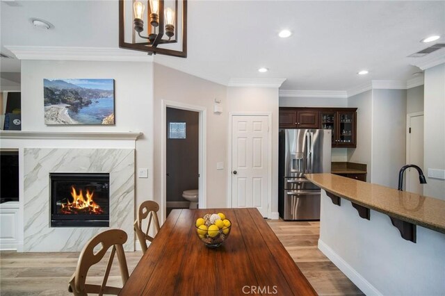 1 Evergreen Rd, Ladera Ranch, CA 92694 - dining area featuring light wood finished floors, recessed lighting, a premium fireplace, ornamental molding, and a chandelier