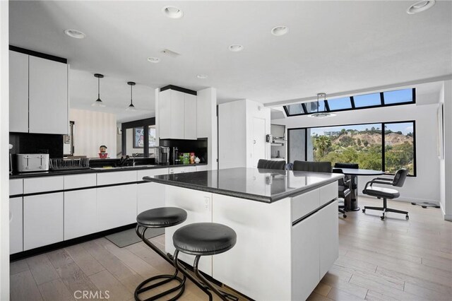 3545 Alana Dr, Sherman Oaks, CA 91403 - kitchen with dark countertops, white cabinets, pendant lighting, light wood-style flooring, and plenty of natural light