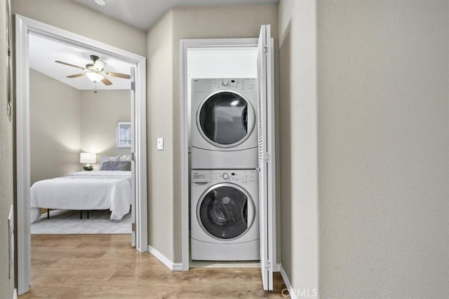 579 Camino Mercado Unit 504, Arroyo Grande, CA 93420 - laundry room with stacked washer and clothes dryer, light wood-style floors, a ceiling fan, baseboards, and a textured wall