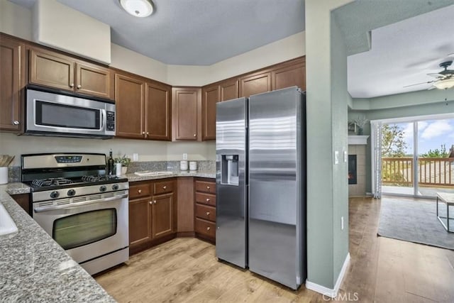 579 Camino Mercado Unit 504, Arroyo Grande, CA 93420 - kitchen with stainless steel appliances, light wood finished floors, ceiling fan, and light stone counters