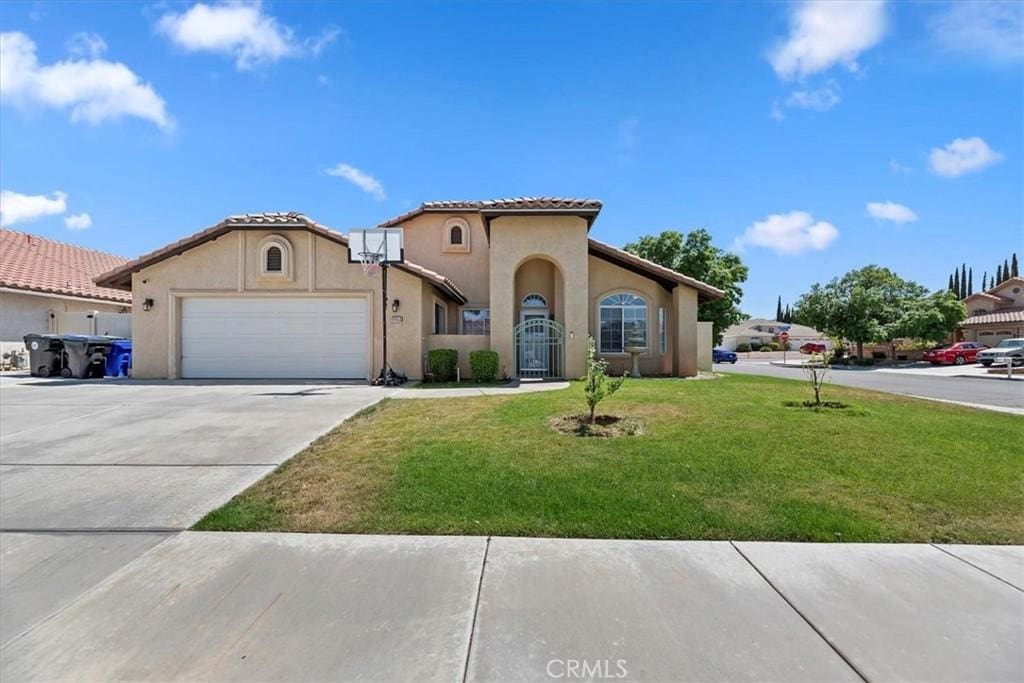 12453 Kokomo Ct, Victorville, CA 92392 - mediterranean / spanish home featuring concrete driveway, an attached garage, a front lawn, and stucco siding