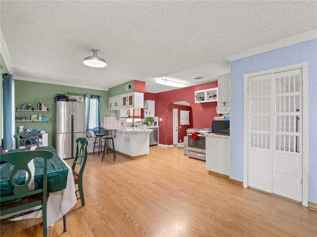 1654 W S Ave, Fresno, CA 93706 - kitchen featuring stainless steel appliances, a textured ceiling, arched walkways, light wood-style floors, and crown molding