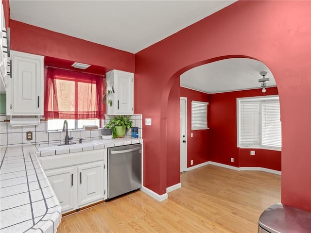 1654 W S Ave, Fresno, CA 93706 - kitchen with stainless steel dishwasher, tile countertops, arched walkways, light wood-type flooring, and white cabinetry