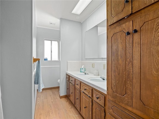 1654 W S Ave, Fresno, CA 93706 - full bath with double vanity, backsplash, wood finished floors, toilet, and crown molding