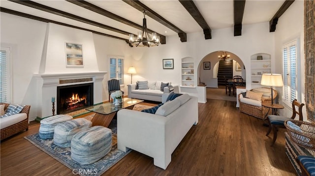 1305 E Balboa Blvd, Newport Beach, CA 92661 - living room with arched walkways, a chandelier, built in shelves, a lit fireplace, and beamed ceiling