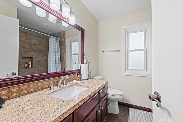20028 Strathern St, Winnetka, CA 91306 - full bathroom with vanity, toilet, baseboards, tiled shower, and stone finish floors