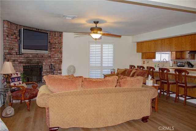 1301 Charterten Ave, Bakersfield, CA 93307 - living area featuring a ceiling fan, wood finished floors, and a brick fireplace