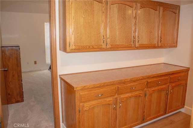 1301 Charterten Ave, Bakersfield, CA 93307 - kitchen featuring brown cabinets, light colored carpet, light countertops, and baseboards