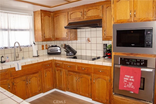 1301 Charterten Ave, Bakersfield, CA 93307 - kitchen with stainless steel appliances, under cabinet range hood, a sink, and brown cabinets