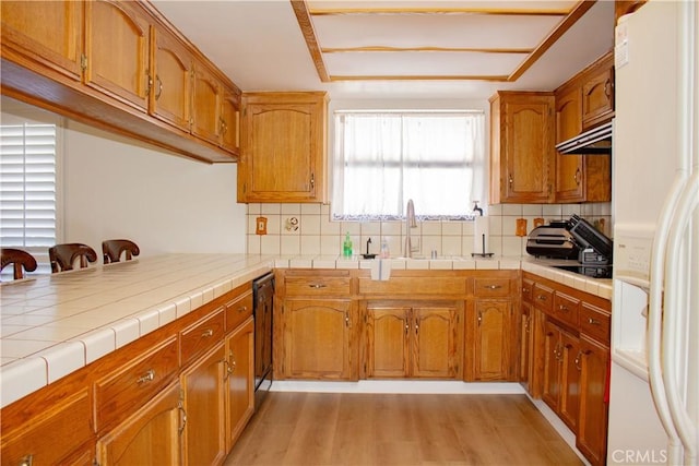 1301 Charterten Ave, Bakersfield, CA 93307 - kitchen with white fridge with ice dispenser, a sink, light wood-style flooring, brown cabinetry, and tasteful backsplash