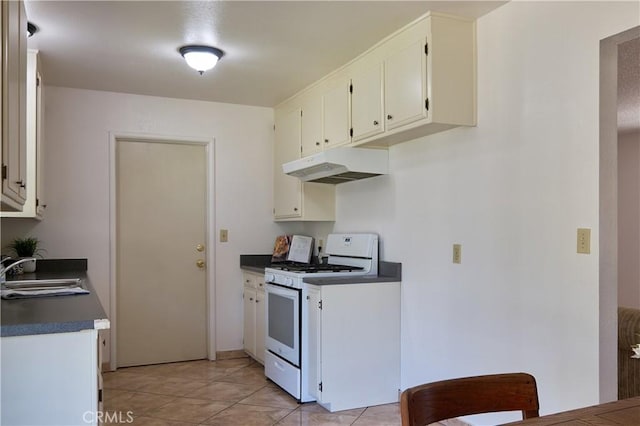 512 Maple St, Willows, CA 95988 - kitchen featuring white gas stove, under cabinet range hood, a sink, dark countertops, and white cabinets