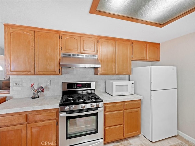 13044 Smith Rd, Phelan, CA 92371 - kitchen featuring under cabinet range hood, white appliances, backsplash, baseboards, and tile counters
