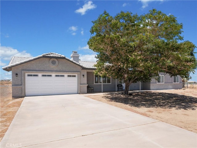 13044 Smith Rd, Phelan, CA 92371 - view of front of property featuring an attached garage, concrete driveway, stucco siding, a tile roof, and a chimney