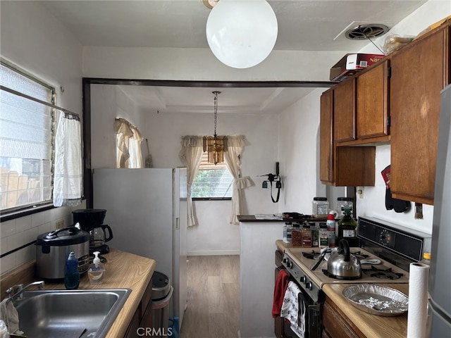 919 Dexter St, Los Angeles, CA 90042 - kitchen with gas range, a sink, wood finished floors, brown cabinets, and backsplash