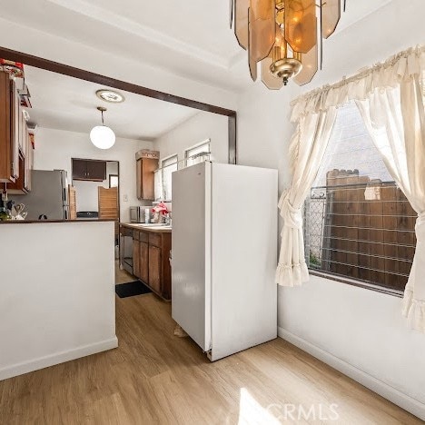 919 Dexter St, Los Angeles, CA 90042 - kitchen with freestanding refrigerator, light wood-style floors, brown cabinetry, and pendant lighting
