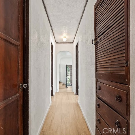 919 Dexter St, Los Angeles, CA 90042 - corridor featuring a textured wall, arched walkways, light wood finished floors, and a textured ceiling