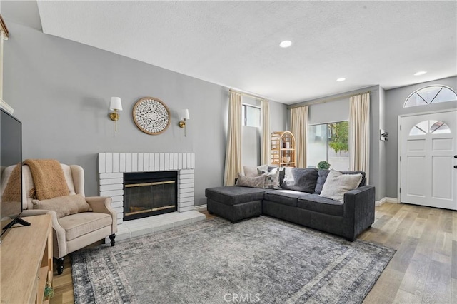 140 W 220th St Unit 105, Carson, CA 90745 - living area featuring wood finished floors, a brick fireplace, recessed lighting, baseboards, and a textured ceiling