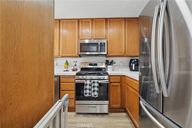 140 W 220th St Unit 105, Carson, CA 90745 - kitchen featuring appliances with stainless steel finishes, tile counters, brown cabinets, and light wood-type flooring