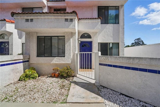 140 W 220th St Unit 105, Carson, CA 90745 - view of front of property featuring stucco siding, a fenced front yard, a gate, and a tiled roof