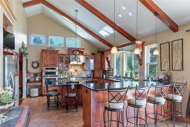 781 Brentwood Dr, Lake Arrowhead, CA 92352 - kitchen featuring brown cabinetry, appliances with stainless steel finishes, beamed ceiling, a kitchen breakfast bar, and tasteful backsplash