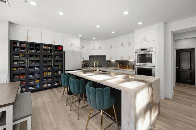 1941 Devaul Ranch Dr, San Luis Obispo, CA 93405 - kitchen featuring stainless steel double oven, light wood-type flooring, freestanding refrigerator, white cabinetry, and recessed lighting