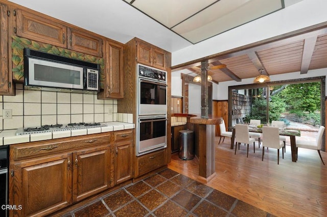 1139 Fairview Dr, La Canada Flintridge, CA 91011 - kitchen featuring white appliances, tile counters, tasteful backsplash, brown cabinets, and wooden ceiling with exposed beams