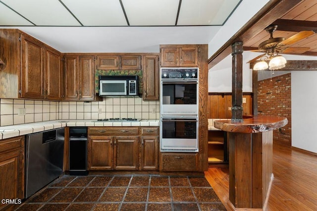 1139 Fairview Dr, La Canada Flintridge, CA 91011 - kitchen featuring tile countertops, appliances with stainless steel finishes, backsplash, ceiling fan, and dark wood-style flooring