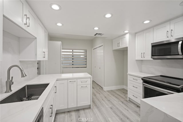 19029 Nordhoff St Unit 103, Northridge, CA 91324 - kitchen with appliances with stainless steel finishes, a sink, light stone counters, light wood-style floors, and recessed lighting