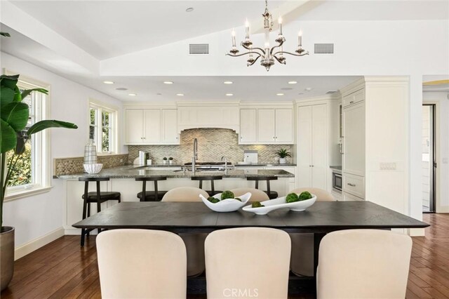 111 Brooks, Laguna Beach, CA 92651 - kitchen with a kitchen bar, decorative backsplash, vaulted ceiling, a chandelier, and dark wood-type flooring