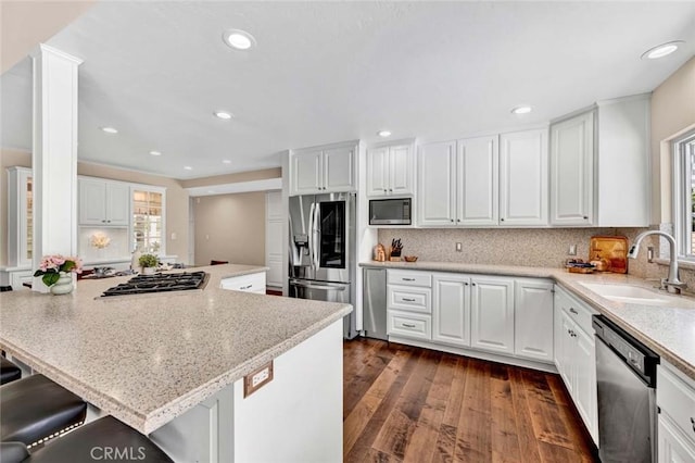 14652 Danborough Rd, Tustin, CA 92780 - kitchen featuring appliances with stainless steel finishes, dark wood-style flooring, white cabinetry, a kitchen bar, and recessed lighting