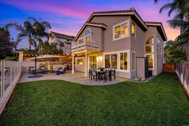 9552 Babauta Rd, San Diego, CA 92129 - back of house at dusk featuring a balcony, an outdoor hangout area, a fenced backyard, stucco siding, and a patio area