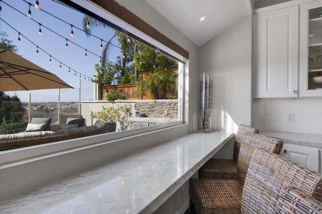9552 Babauta Rd, San Diego, CA 92129 - detailed view of light stone counters, glass insert cabinets, decorative backsplash, and white cabinetry