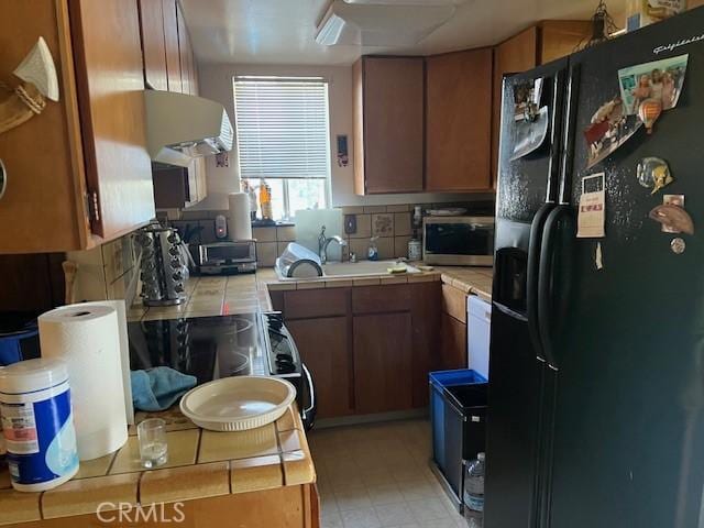 13238 Ebbtide, Clearlake Oaks, CA 95423 - kitchen featuring black refrigerator with ice dispenser, tile counters, extractor fan, brown cabinets, and light floors
